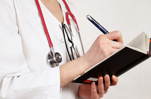 Doctor writes in working notebook