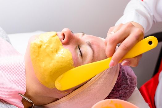 Applying a golden mask on the face after the cleansing procedure, an aromatic mask to moisturize, rejuvenate and lighten the skin. new