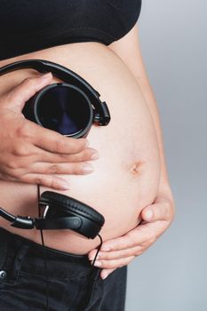 Pregnant woman holding headphones on her belly