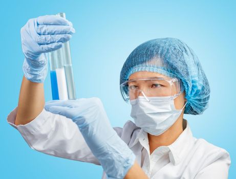 Laboratory female assistant examines three tube of different colors on a blue background