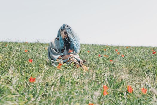 Beautiful young woman with blue hair rests on red tulips meadow.