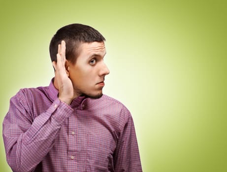 Young man listening with hand on ear with a serious expression