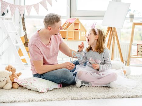 Happy daughter having fun with father in children's room