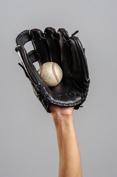 catching baseball with leather baseball glove over gray background