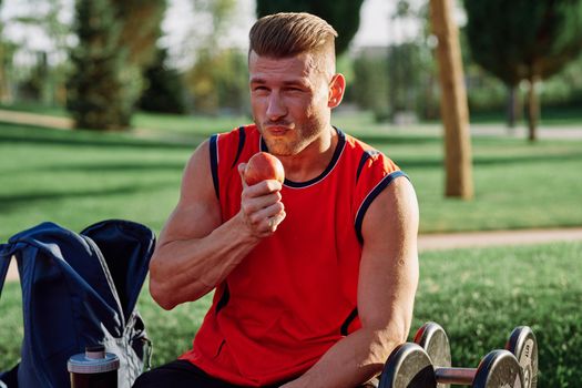 sporty man resting in the park on a bench having a snack. High quality photo