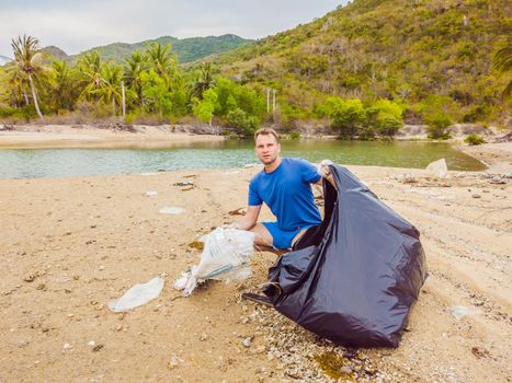 Man in gloves pick up plastic bags that pollute sea. Problem of spilled rubbish trash garbage on the beach sand caused by man-made pollution and environmental, campaign to clean volunteer in concept.