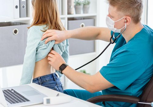 Doctor listening little patient by phonendoscope in clinic