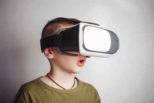 Boy playing mobile game app on device virtual reality glasses on white background. Boy action and using in virtual headset, VR box for use with smart phone. Contemporary technology concept, close up