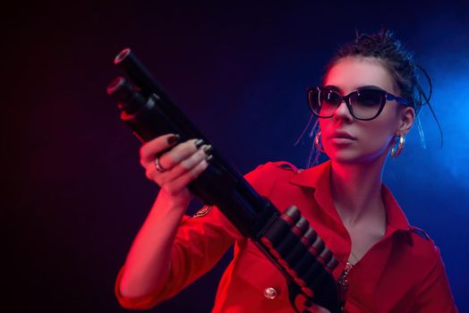 bright brunette in a red jumpsuit with a shotgun on a dark background in neon light