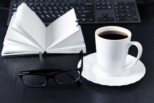 Business Office scene, laptop and notebook with coffee on black desk