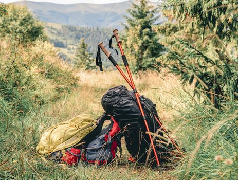 Trekking sticks and backpacks lying on mountain trail