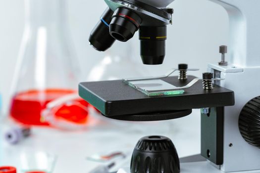 Close up photo of a microscope lenses examining glass sample in laboratory