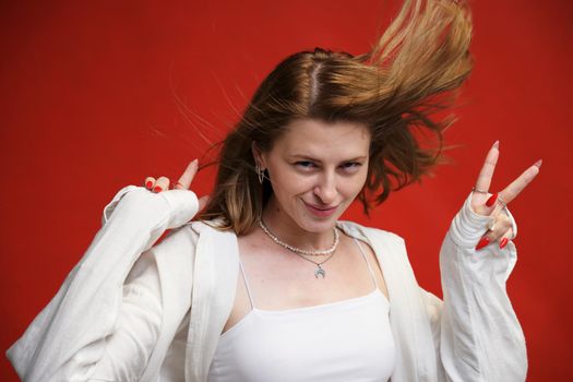 Portrait of a cute model shows v on a red background with a smile