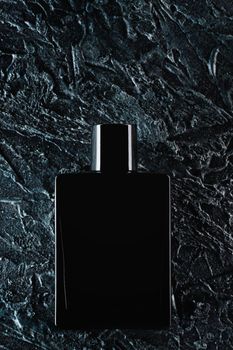 Silhouette of a black bottle of eau de toilette for men on a dark background. Advertising photo of perfumes. Dark style. Layout.