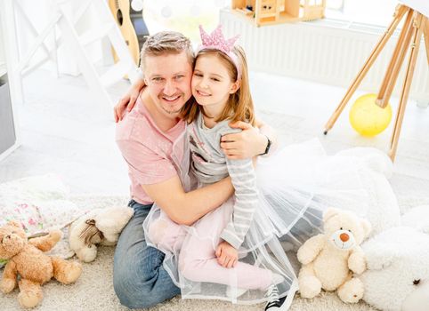 Top view of cute little girl cuddling with loving father in light room