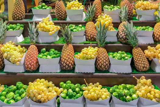 Fresh grapes pineapples and Brussels sprouts on the grocery store in the supermarket in France