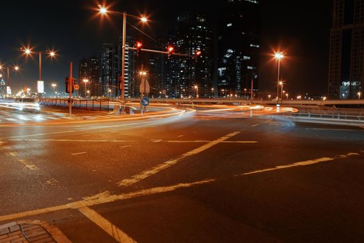 Empty asphalt road with modern buildings at night in Dubai, UAE