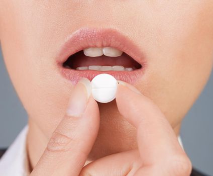 Round white pill is on the lower lip, close-up