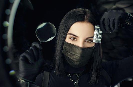 brunette wearing a protective black coronavirus mask with pills and a magnifying glass