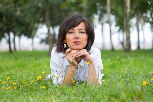 Young woman lying on a meadow with daisy in a summer park