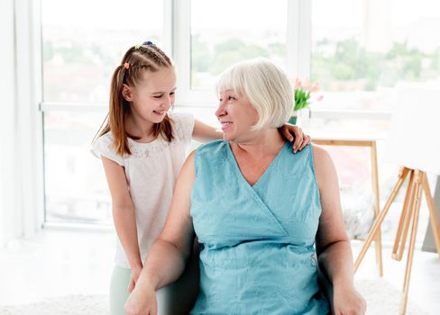 Smiling grandmother with cute granddaughter at home