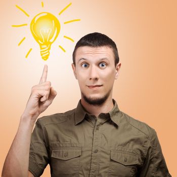 Young man points a finger at the sign light bulbs. On a orange background