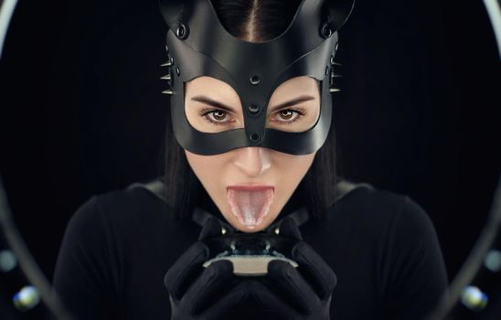 the woman in a black body belt and cat mask with a bowl of milk