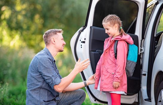 Father meeting little school girl after classes on parking