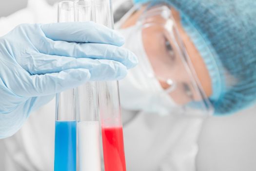 Woman scientist examines three tubes in the laboratory, focus on the test tubes