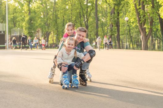 Sibling sisters and their father posing and roller skating in protective form together on weekend