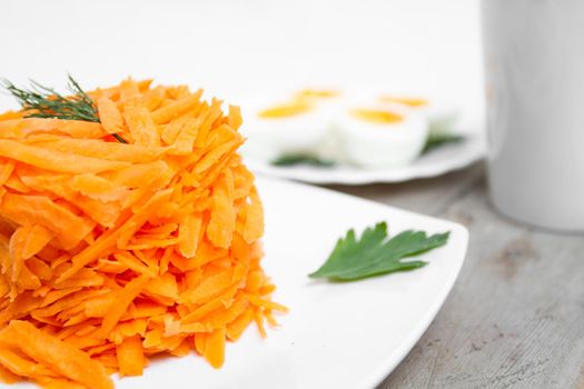 Carrot salad, boiled eggs, cup on a wooden table