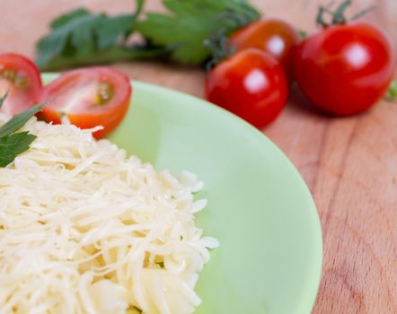 A dish of macaroni with cheese, tomato on wooden table
