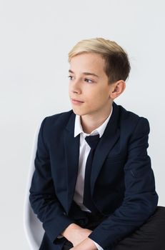 Portrait of stylish school boy teenager in white shirt and jacket against white background with copy space