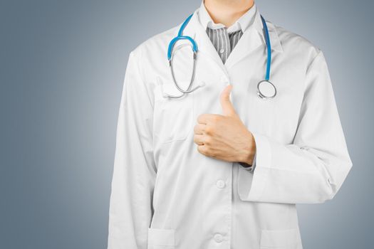 Male doctor shows gesture thumbs up on a gray background, space for text