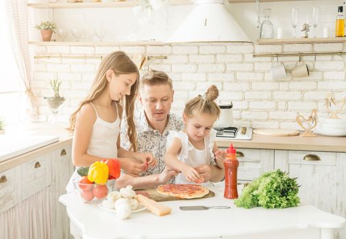 dad with two little daughters preparing pizza in the kitchen