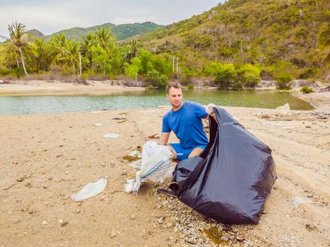 Man in gloves pick up plastic bags that pollute sea. Problem of spilled rubbish trash garbage on the beach sand caused by man-made pollution and environmental, campaign to clean volunteer in concept.