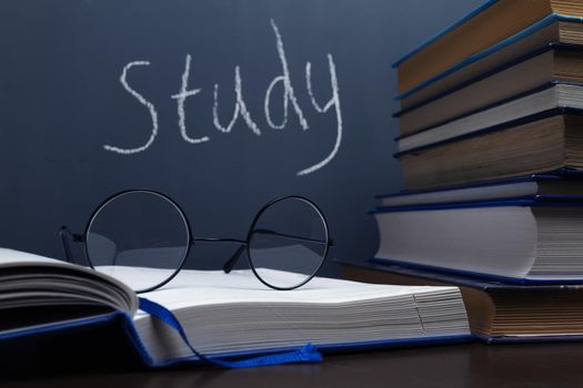Stack of books and glasses on a blackboard background