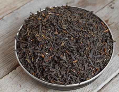 Black leaf tea on a wooden background, top view