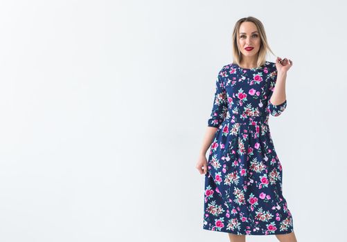 Fashionable young woman in beautiful dress posing at studio. Isolated over white.