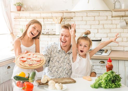 dad with two little daughters preparing pizza in the kitchen