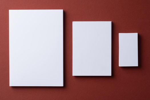 Blank white business cards on burgundy paper background, top view
