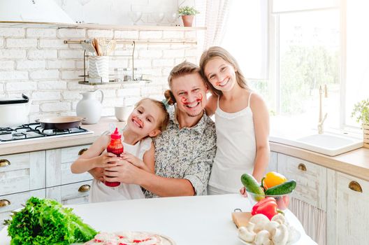 dad with two little daughters preparing pizza in the kitchen