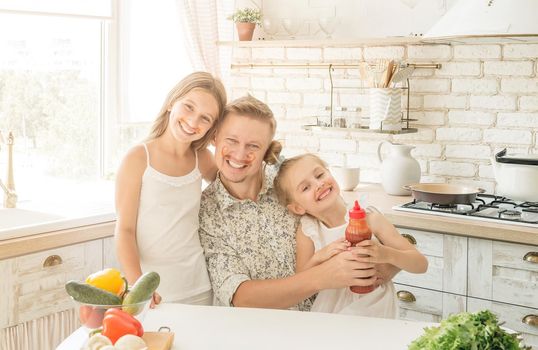 dad with two little daughters have a fun in the kitchen