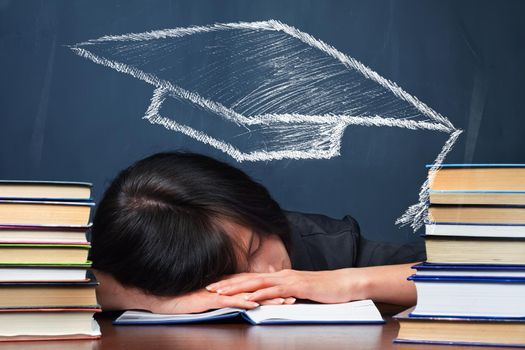 Tired woman with drawing educational hat sleeps between the stacks of books