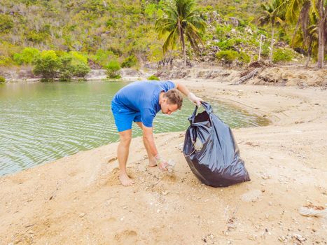 Man in gloves pick up plastic bags that pollute sea. Problem of spilled rubbish trash garbage on the beach sand caused by man-made pollution and environmental, campaign to clean volunteer in concept.