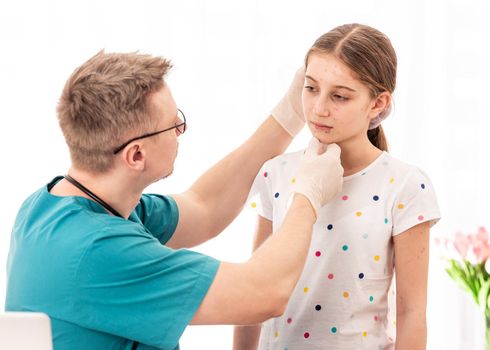 Qualified medic accurately checking sick girls appearance, on white background