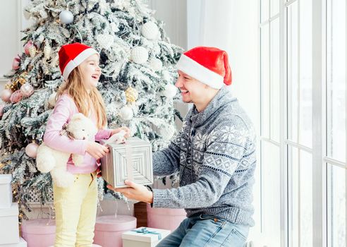 Smiling father giving little daughter christmas gift