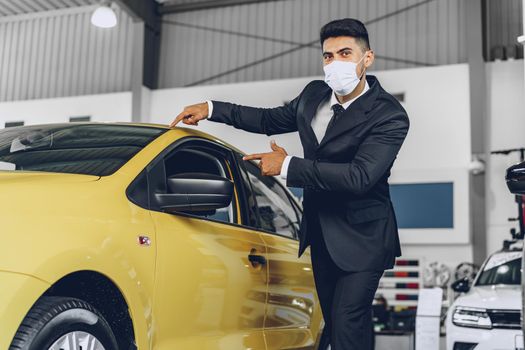 Man car dealer wearing protective medical mask on his working place, coronavirus prevention concept