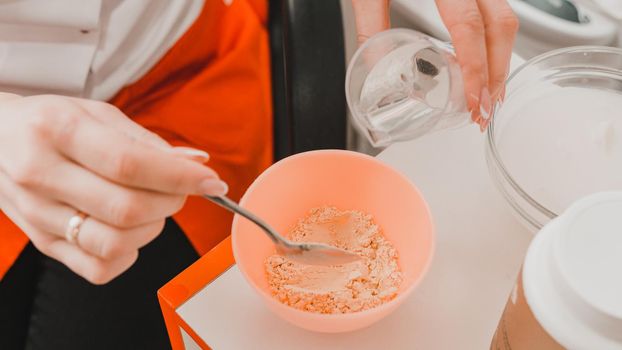 The beautician mixes the golden mask before applying on the face, mixing the mask in a bowl. new