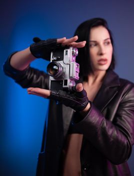 the brunette photographer girl in underwear and a leather raincoat poses in a photo studio with a camera